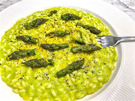 Risotto agli asparagi e limone impiattato con punte di asparago e scorza di limone