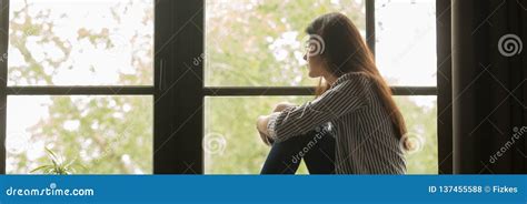 Ragazza che guarda fuori dalla finestra con espressione pensierosa