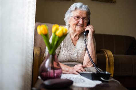 Donna anziana che parla al telefono con espressione preoccupata