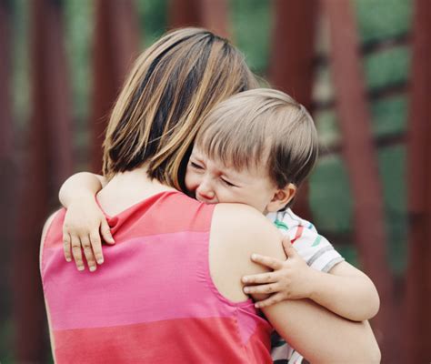 Bambino che piange aggrappato a un genitore