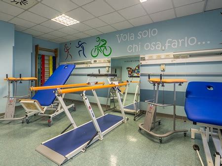 Immagine di una palestra di riabilitazione moderna con attrezzature robotizzate e pazienti che svolgono esercizi.