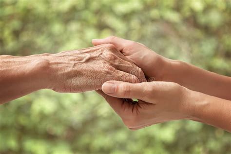 Mani di un anziano che stringono mani di un familiare