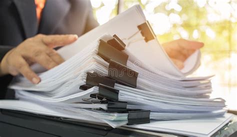 Persona che lavora in un ufficio con pile di documenti ordinate
