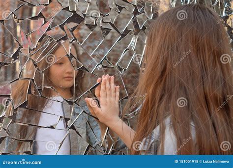 Donna che si guarda in uno specchio rotto
