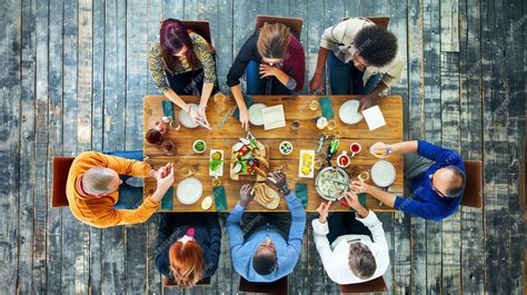 Persone che mangiano con le mani attorno a un tavolo comune